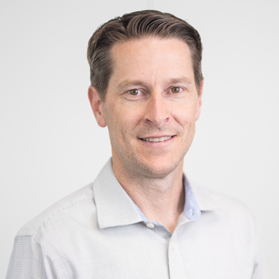 team-ben Professional headshot of man in light blue button-up shirt against white background.