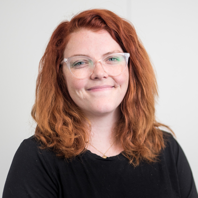 team-haley Person with red wavy hair wearing glasses and black shirt against white background.